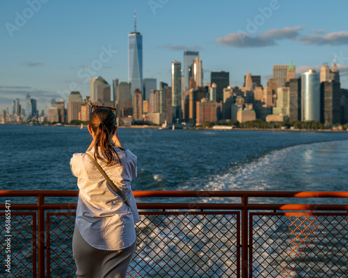 Woman looking around from Staten island ferry and taking photo about Lower Manhattan in New York city.