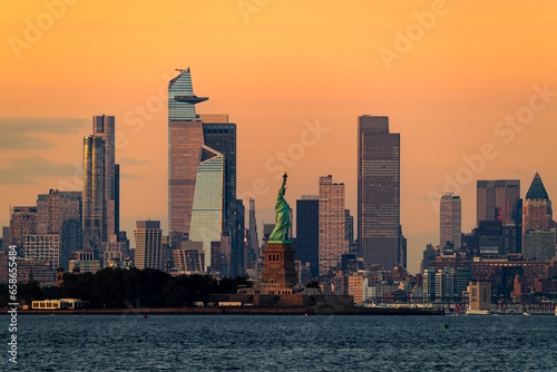 Cityscape landscape in golden hour about New York. included the Statue of liberty. Lady liberty is on the middle New York Skyscrapers is on the background included the famous Edge observation deck too