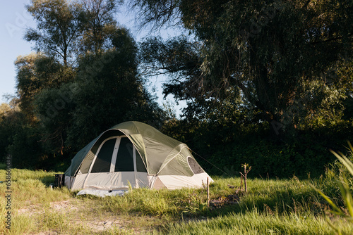 A green tent stands among beautiful nature on sunny days. Camping in summer