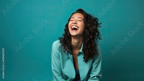 Lighthearted Laugh in Teal. Model chuckling against a refreshing teal background, evoking a carefree and lively spirit.