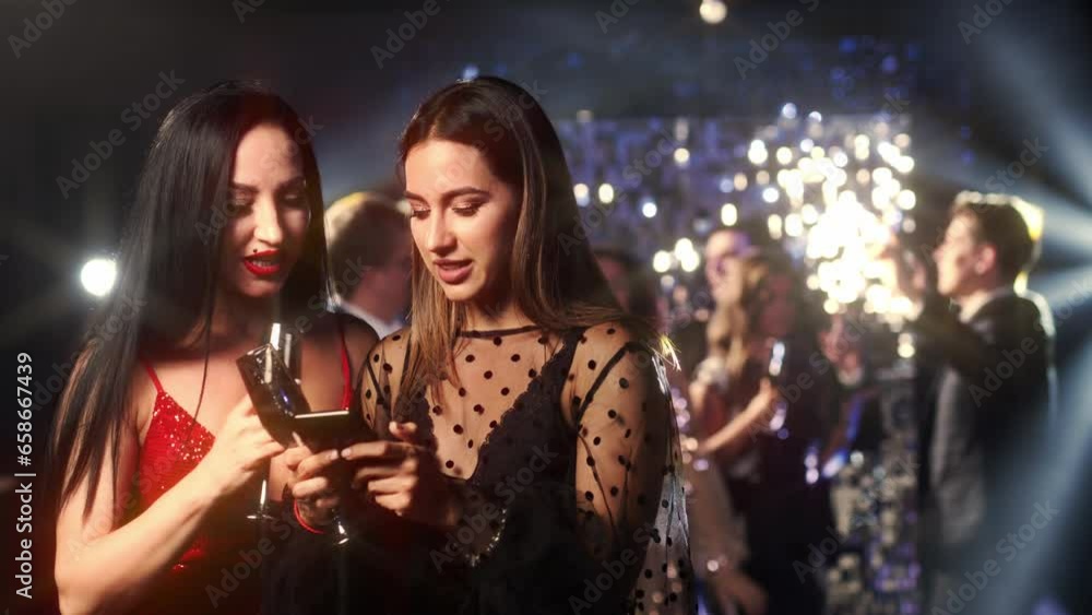 Friends or women in a nightclub talking and looking at the phone. Girls and neon light for traveling with Internet connection.