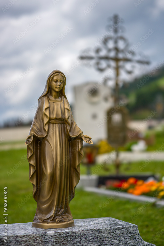 eine goldene Madonna auf einem Friedhof