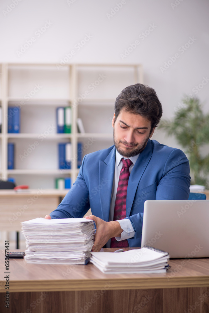 Young male employee and too much work in the office Young male employee and too much work in the office