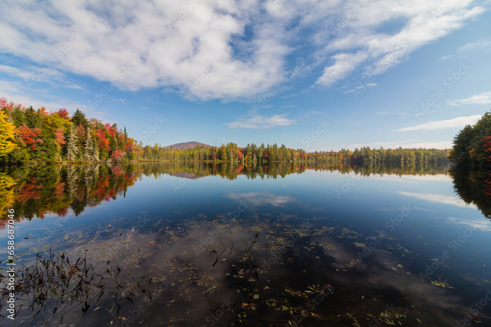 Adirondack lake in St Regis Wilderness with peak fall foliage on a peaceful calm morning