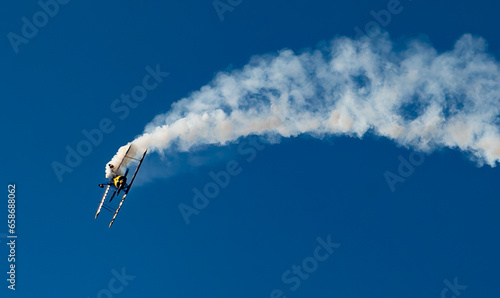 A Biplane is turning upside down with a trail of smoke.