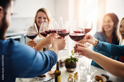 Group of friends toasting with red wine glasses at a festive lunch party