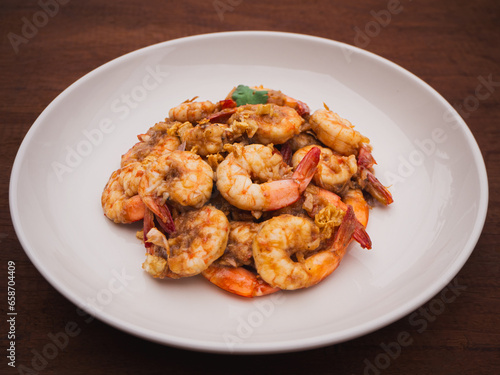 Stir fried shrimps with garlic and white pepper in plate on wooden table. Thai Food