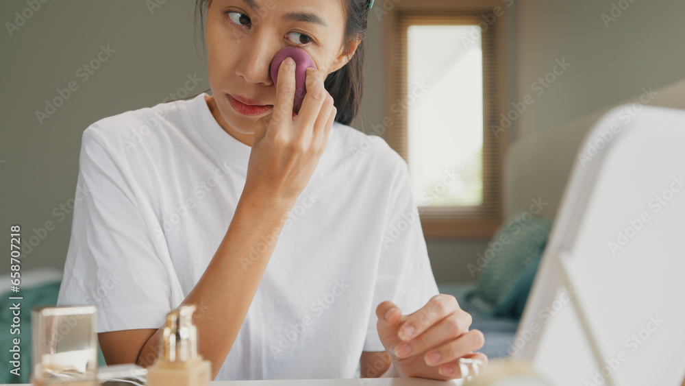 Young Asia girl beauty blogger, look at the mirror, makeup use sponge apply foundation on her face in bedroom. Lifestyle and people, Make up Natural look, Skin Care Cosmetics, Morning routine concept. Young Asia girl beauty blogger, look at the mirror, makeup use sponge apply foundation on her face in bedroom. Lifestyle and people, Make up Natural look, Skin Care Cosmetics, Morning routine concept.