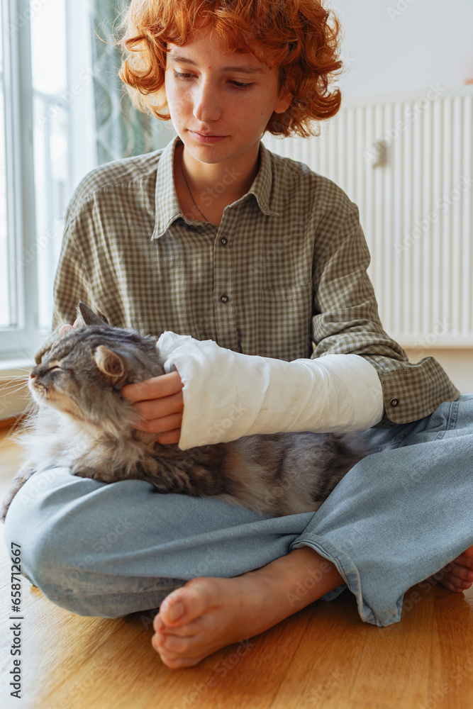 Obraz premium teenager with broken arm in cast and pet cat