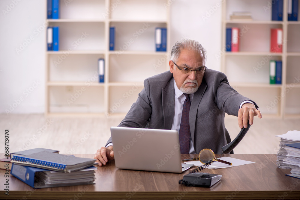 Old male employee working in the office Old male employee working in the office