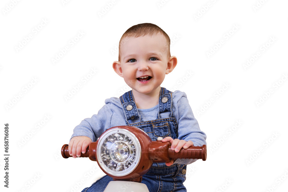 Happy baby boy rides a plastic children motorcycle in the playroom, isolated on a white background. A smiling child drives a moped toy, isolated on a white background. Kid age one year Happy baby boy rides a plastic children motorcycle in the playroom, isolated on a white background. A smiling child drives a moped toy, isolated on a white background. Kid age one year