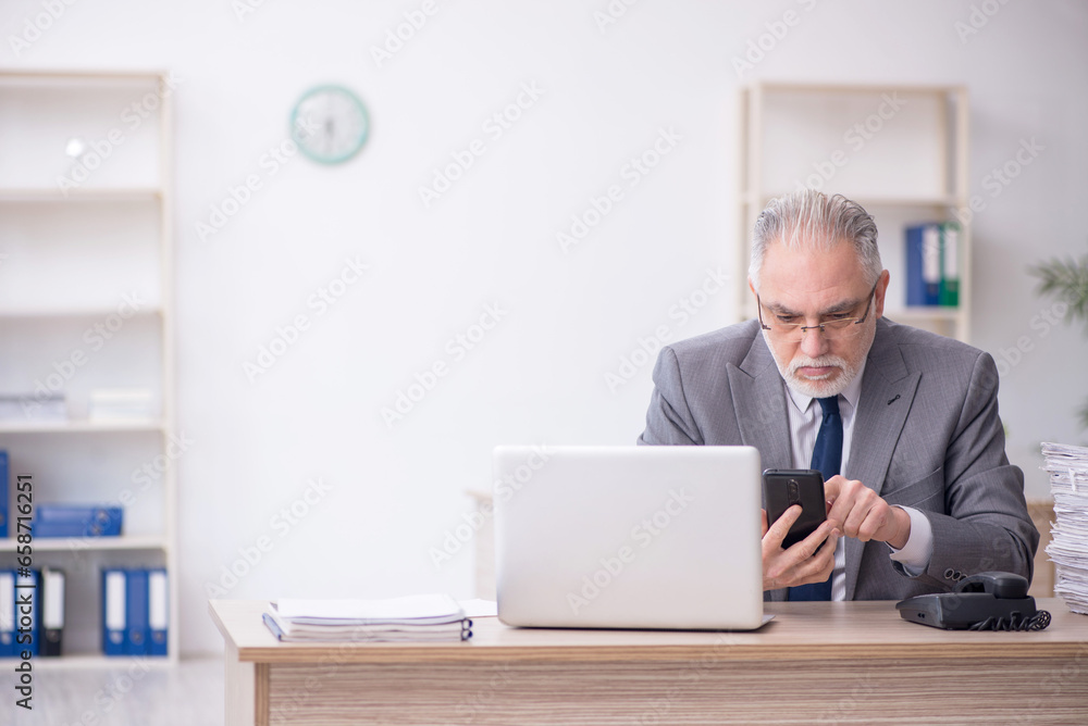 Old male employee working in the office Old male employee working in the office