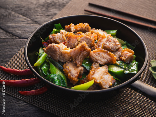 Stir fried crispy pork with kale and oyster sauce in pan on wooden table. Asia Food