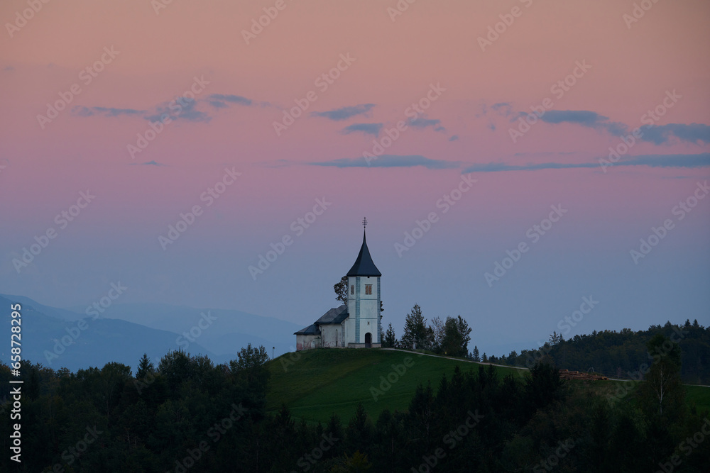 Fototapeta premium Twilight over The Church of St. Primoz and Felicijan in the village of Jamnik in the Slovenian Alps. Beautiful colorful sky.