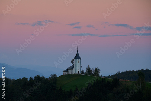 Twilight over The Church of St. Primoz and Felicijan in the village of Jamnik in the Slovenian Alps. Beautiful colorful sky.