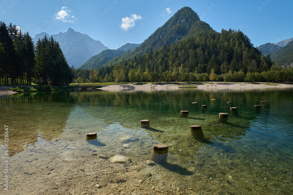 Lake Jasna in Slovenia with crystal clear turquoise water and mountains in the background.