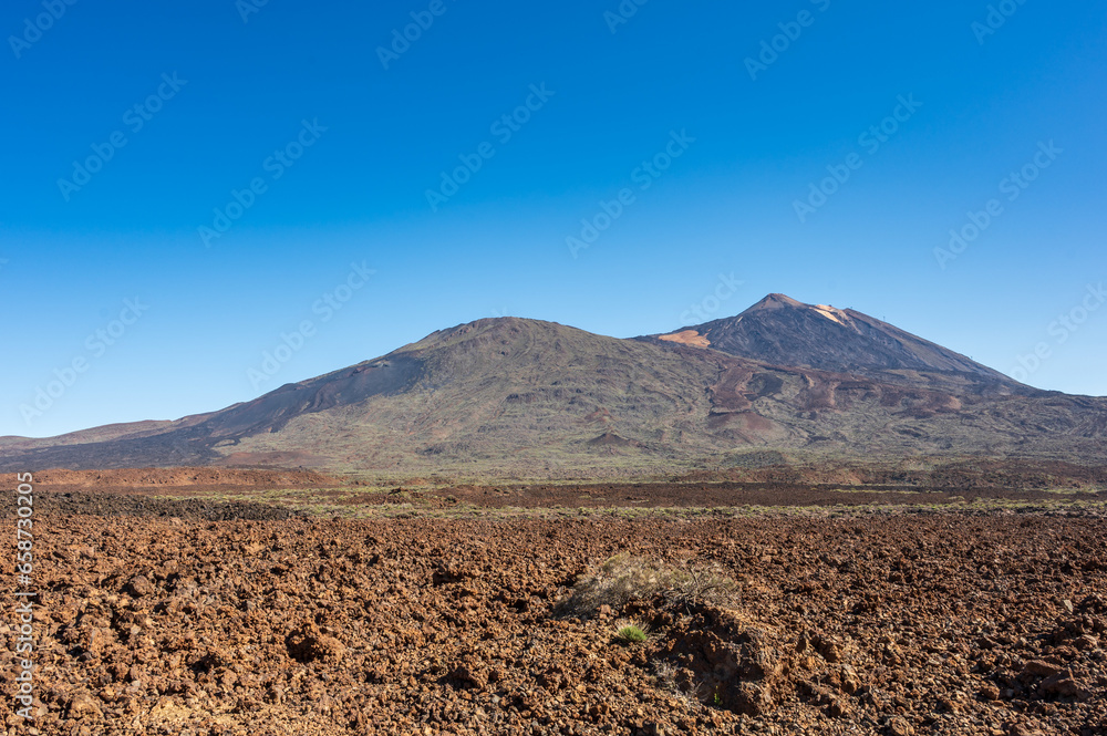 View of Mount Teide, Tenerife.  The highest point in Spain.  The brown  landscape is barran and volcanic, set against a deep blue sky