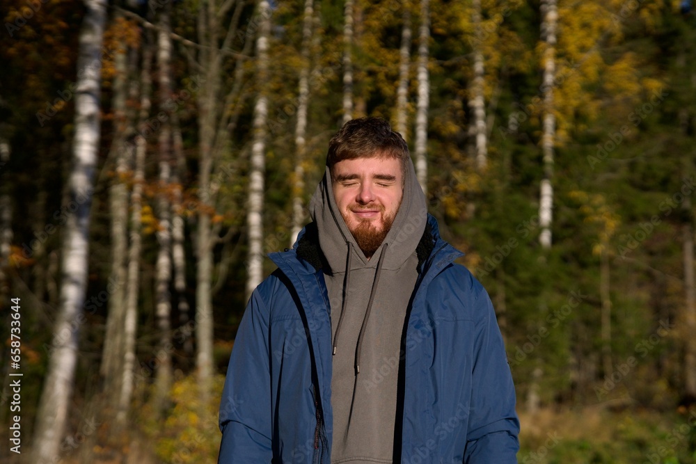 Portrait of young happy man in golden autumn forest at sunny fall day Portrait of young happy man in golden autumn forest at sunny fall day