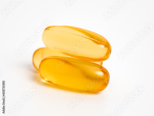 Three isolated oil capsules of omega 3, omega 6, omega 9, fish oil or vitamin on white background. Fish oil vitamins and supplements in therapy, diet and healthy lifestyle. Close up