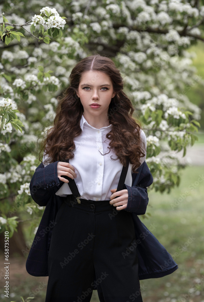 Young business lady in a jacket and suspenders in a blooming spring park Young business lady in a jacket and suspenders in a blooming spring park