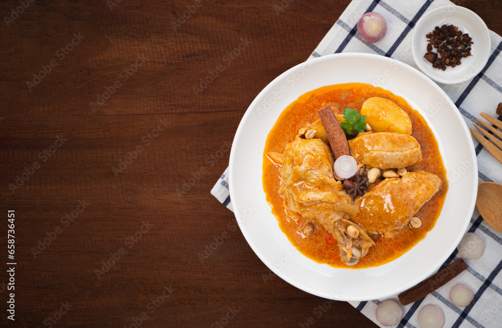 Top view of massaman curry with chicken and potatoes in plate on wooden background. Thai Food