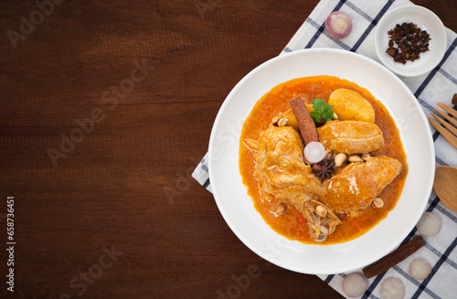 Top view of massaman curry with chicken and potatoes in plate on wooden background. Thai Food