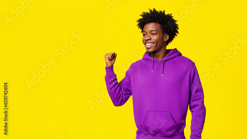 african american man smiling, wearing violet sweatshirt on yellow background, with copy space photo