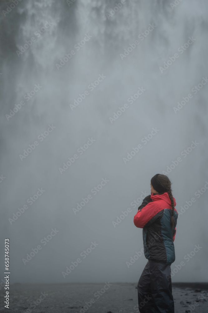 Obraz premium Girl standing in a glacial waterfall in Iceland