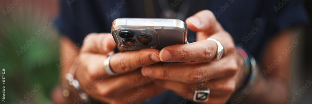 Close-up of male hands in bracelets and rings. Man is using mobile phone. Guy writes message on his smartphone - obrazy, fototapety, plakaty 