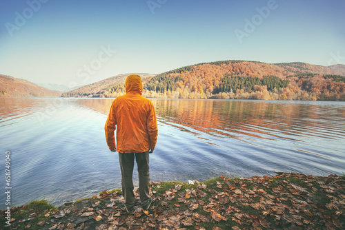 A man stands on the shore of a mountain lake in autumn © vvvita