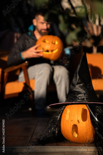man carving Halloween pumpkin on sunny terrace