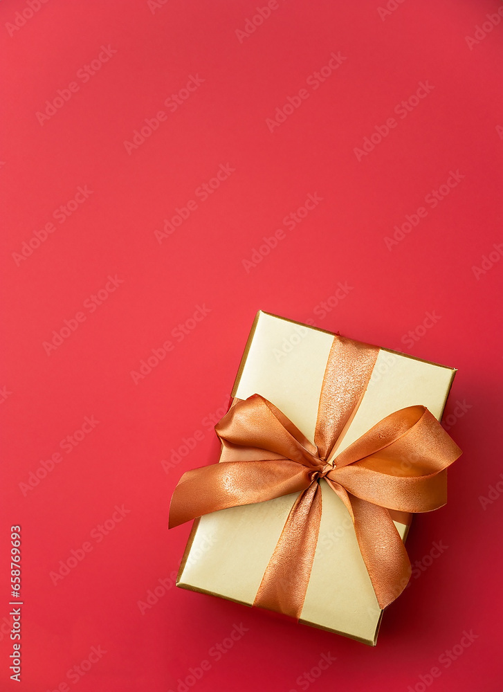 Gift box with a golden satin ribbon and a bow on a red background. Generative AI Gift box with a golden satin ribbon and a bow on a red background. Generative AI