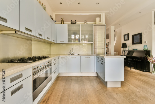 a kitchen with white cabinets and wood flooring in the middle of the room  there is a tv on the wall