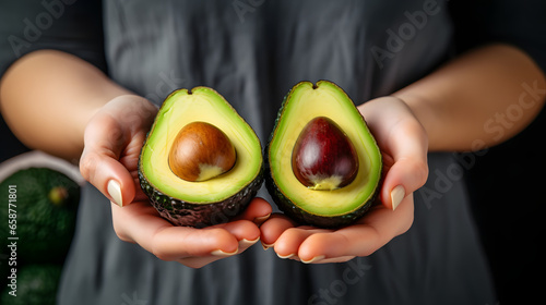 Avocado halves in a female hand in the kitchen.