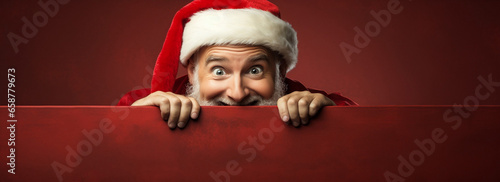 Santa Claus spreading Christmas cheer from behind a festive red wall