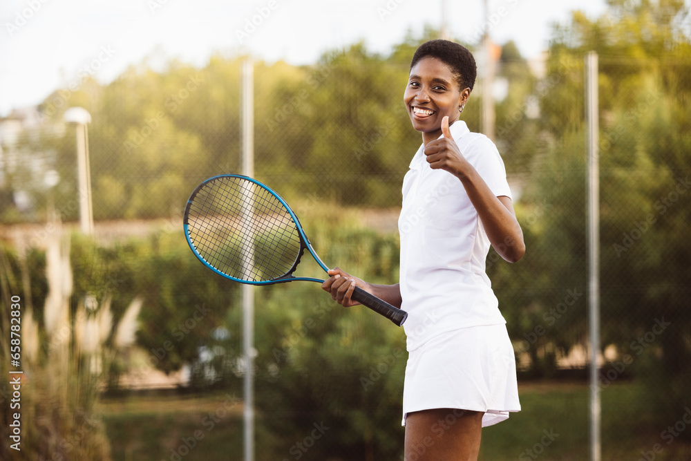 Young beautiful smiling woman playing a tennis match. Sportswoman with a tennis racket playing on outdoor tennis court.