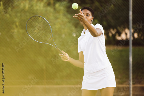 Young beautiful woman playing a tennis match. Sportswoman hitting a serve on outdoor tennis court. © jordi