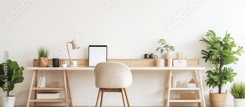 Stylish and boho open work space with wooden desk chair lamp laptop white shelf design elegant accessories botany minimalistic decor with plants With copyspace for text