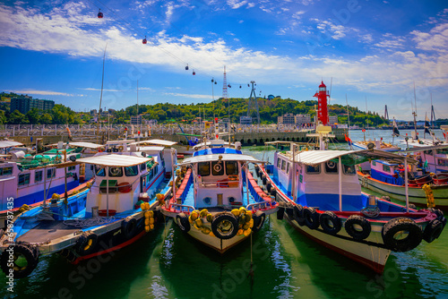 Fotografie Fishing trawlers moored at Hamel Lighthouse harbor under the cable cars in Yeosu