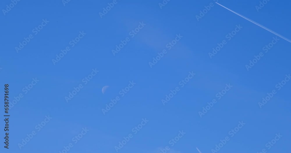 Airplane flying on deep blue sky with chemical direction trails, view from a distance