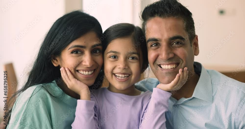 Close up portrait of cheerful loving Indian couple posing with child. Parents and little adorable daughter smile look at camera. Adoption, custody, upbringing, family love and ties, happy parenthood Close up portrait of cheerful loving Indian couple posing with child. Parents and little adorable daughter smile look at camera. Adoption, custody, upbringing, family love and ties, happy parenthood