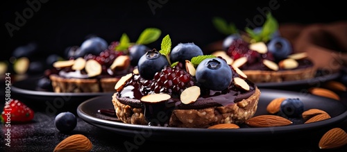 Raw vegan dessert made of dates and cashew chocolate cream topped with almonds pecans and blueberries With copyspace for text