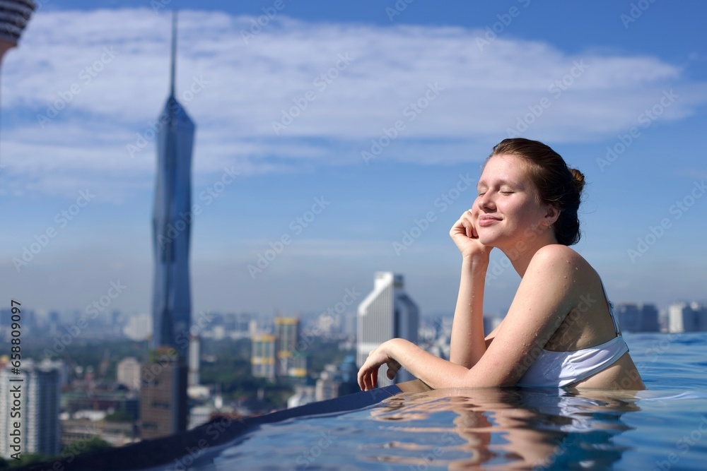 Portrait of happy young woman in swimming pool on the rooftop of skyscraper hotel with beautiful city urban view Portrait of happy young woman in swimming pool on the rooftop of skyscraper hotel with beautiful city urban view