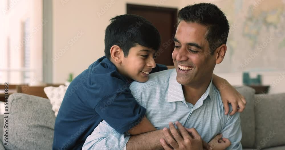 Loving middle-aged daddy spend carefree time with little 8s son, sitting together on couch tickling, laughing, hugging, having fun on weekend. Indian family pastime at home, happy fatherhood, leisure Loving middle-aged daddy spend carefree time with little 8s son, sitting together on couch tickling, laughing, hugging, having fun on weekend. Indian family pastime at home, happy fatherhood, leisure