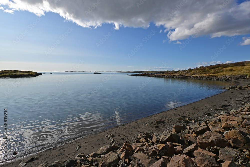 Tranquil bay of water on Borgarnes, Iceland coast under sunny autumn sky with framing cloudscape.