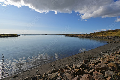 Tranquil bay of water on Borgarnes, Iceland coast under sunny autumn sky with framing cloudscape.