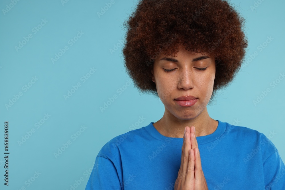 Woman with clasped hands praying to God on light blue background. Space for text Woman with clasped hands praying to God on light blue background. Space for text