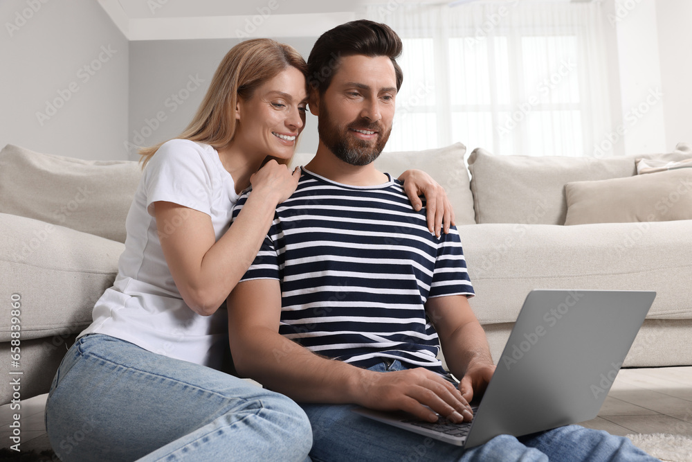 Happy couple with laptop on floor at home Happy couple with laptop on floor at home