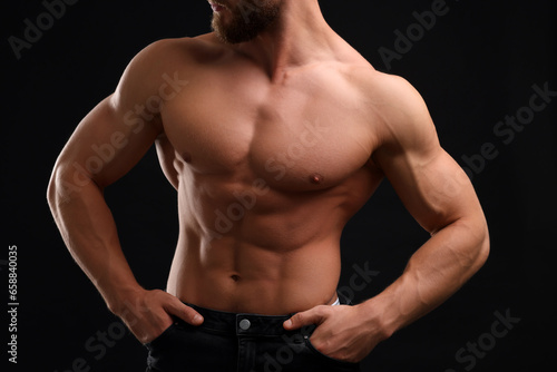 Muscular man showing abs on black background, closeup. Sexy body