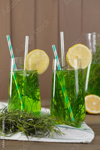 Glasses of refreshing tarragon drink with lemon slices on wooden table photo